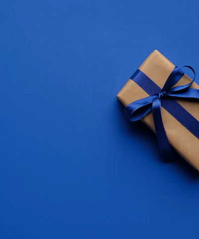 Brown leather key ring with brass metal loops and rivets on wood table.