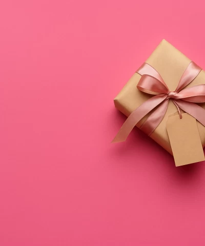 Brown leather key ring with brass metal loops and rivets on wood table.